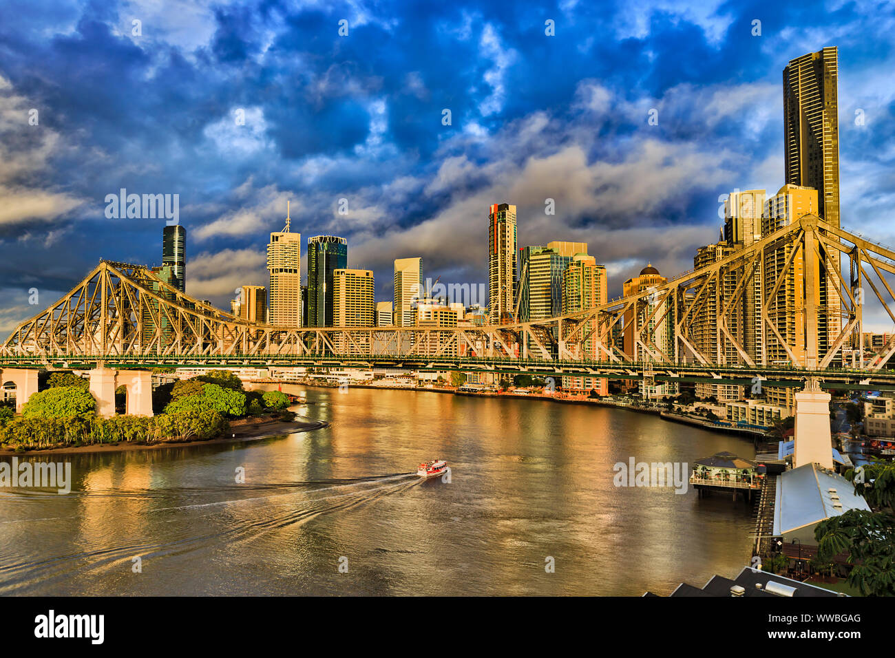 Storia ponte attraverso il fiume Brisbane davanti la città di Brisbane CBD di alto-aumento di business e appartamento torri sotto il blu cielo nuvoloso e traghetti passeggeri pas Foto Stock