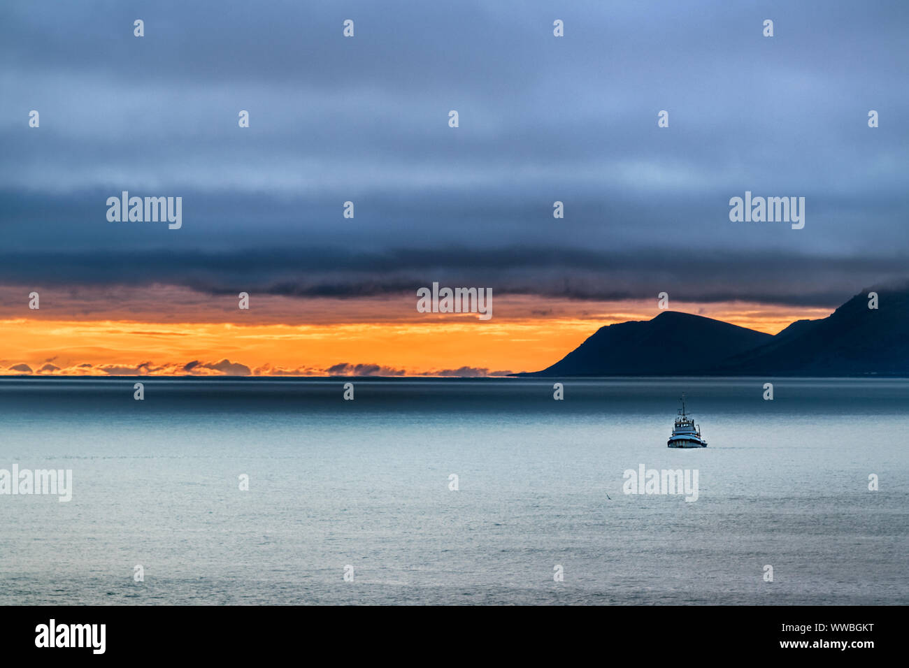 Lo scenario di una piccola nave sul mare di Bering e St Lawrence isola sullo sfondo al tramonto in un giorno di tempesta, Alaska. Foto Stock