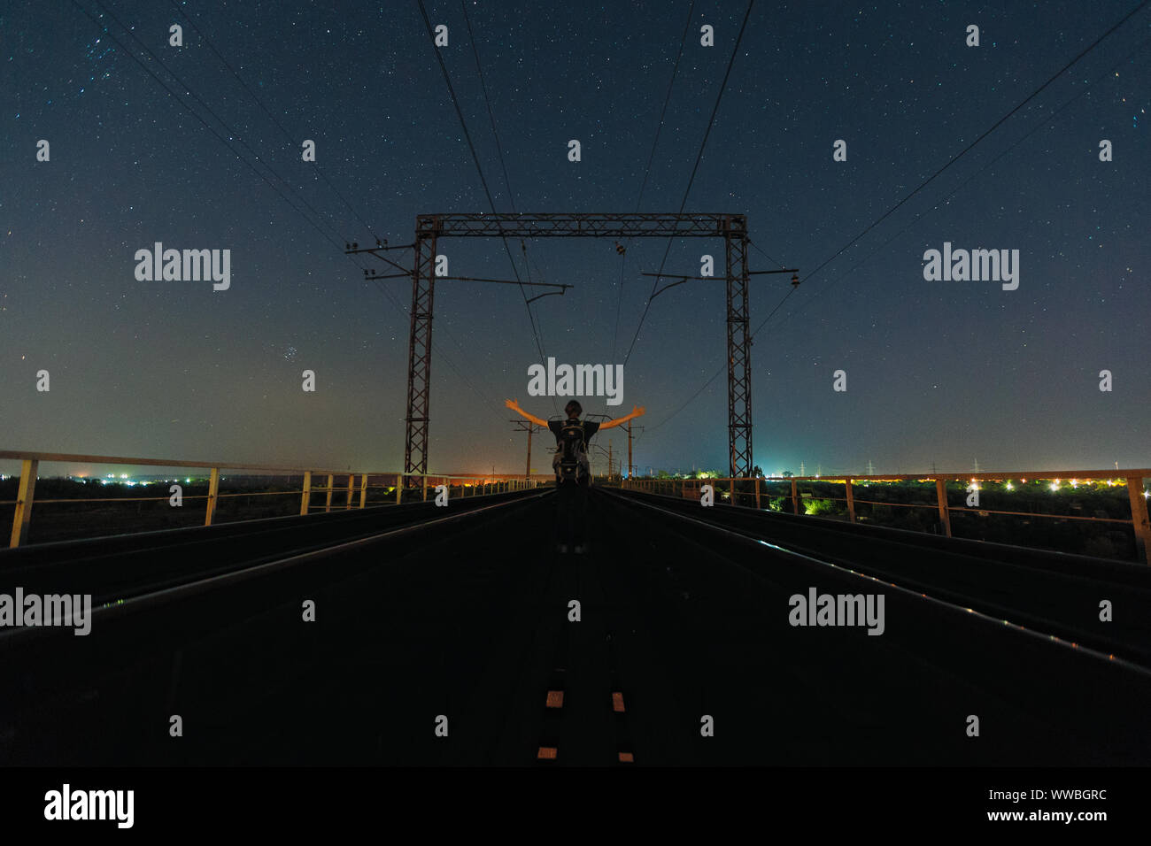 Traveler stare tra due ferrovie e la visione di notte il cielo stellato. Alla notte. Vista posteriore Foto Stock