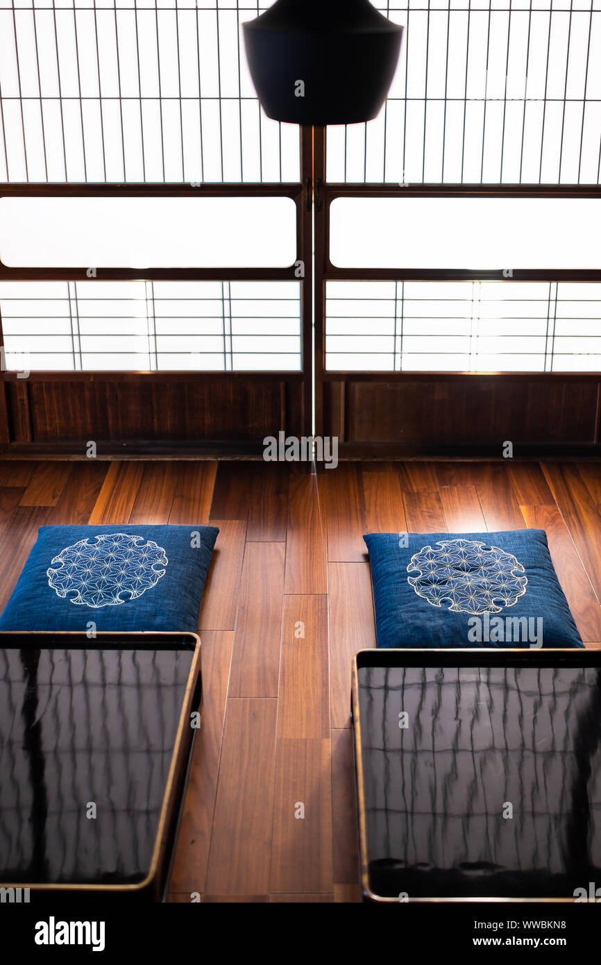 Tradizionale Giapponese casa machiya ryokan ristorante con nero laccato tavolo in legno con cuscini cuscino, lampada e scorrimento delle porte della carta con naturale Foto Stock