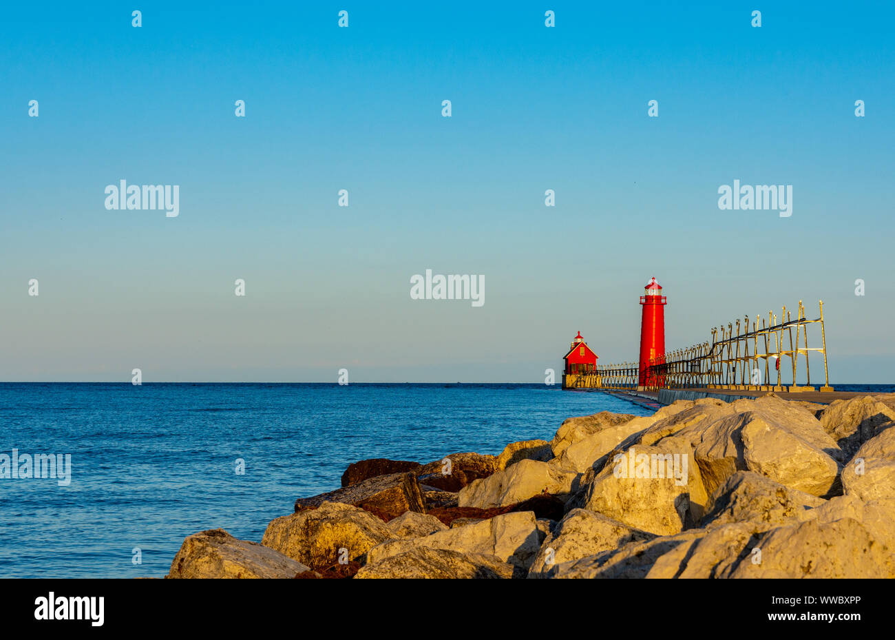 Il sole dorato di una mattina d'estate splende sul faro rosso sul lago Michigan a Grand Haven, Michigan. Foto Stock