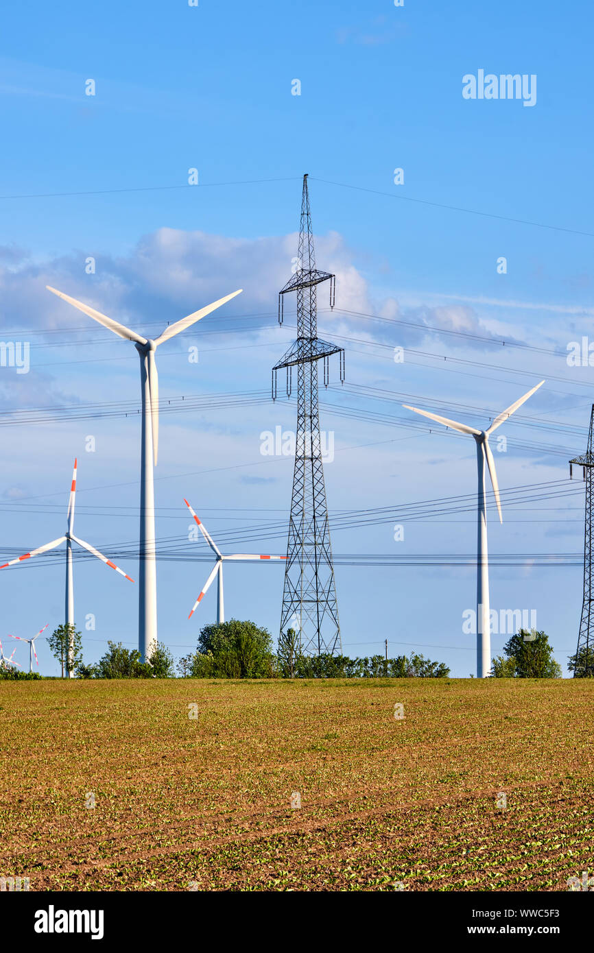 Un traliccio di elettricità e generatori di energia di vento visto in Germania Foto Stock