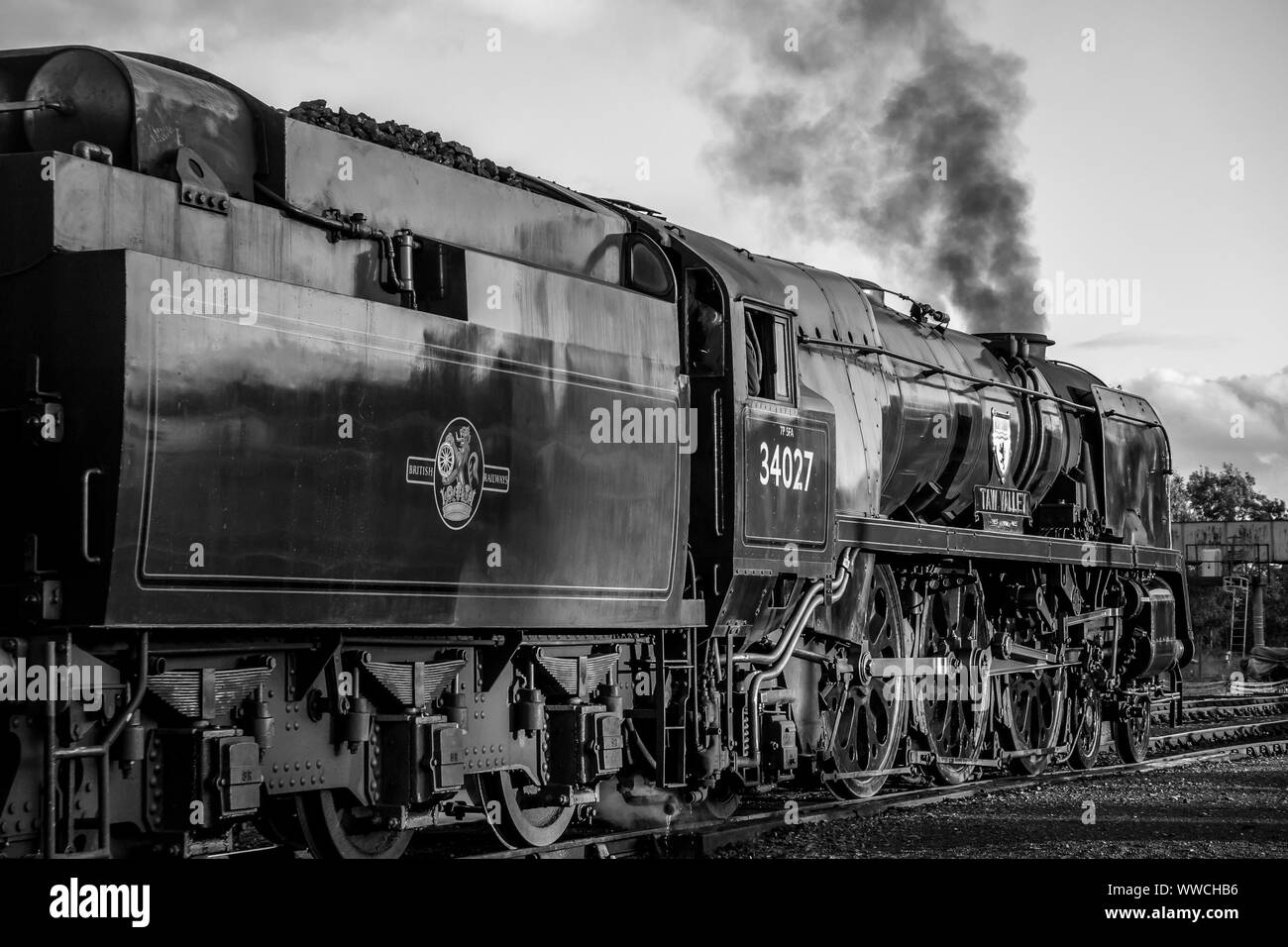 Moody, bianco e nero, vista laterale primo piano della locomotiva a vapore inglese d'epoca Taw Valley 4027 lasciando Severn Valley Heritage ferrovia Kidderminster stazione. Foto Stock