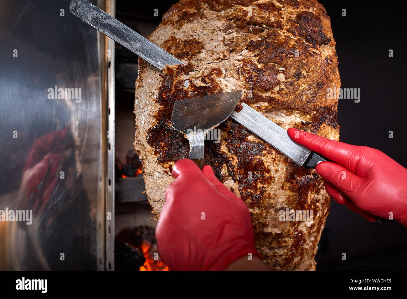 Fritti di carne su uno spiedino per la cottura di donatori o shawarma. ook mani di close-up di tagli di carni in sottile e SLI Foto Stock