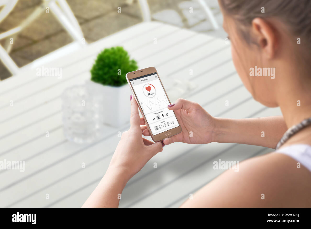 Ragazza misurare la frequenza cardiaca e il parametro SpO2 con smart phone il sensore e il concetto di app. Foto Stock