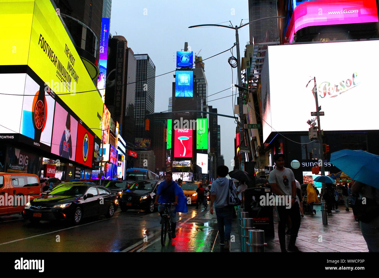 Il traffico di pedoni, ciclisti e automobili trudges attraverso Times Square in un pomeriggio piovoso. Manhattan su luglio 31st, 2019 a New York, Stati Uniti d'America. (Foto di Foto Stock