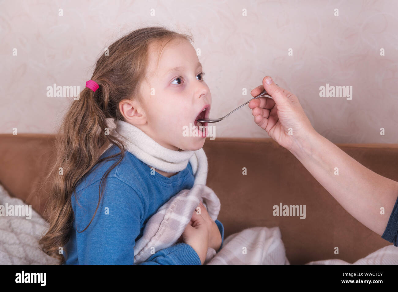 Bambino di prendere la medicina. Malata con sciarpa giacente sul letto Foto Stock