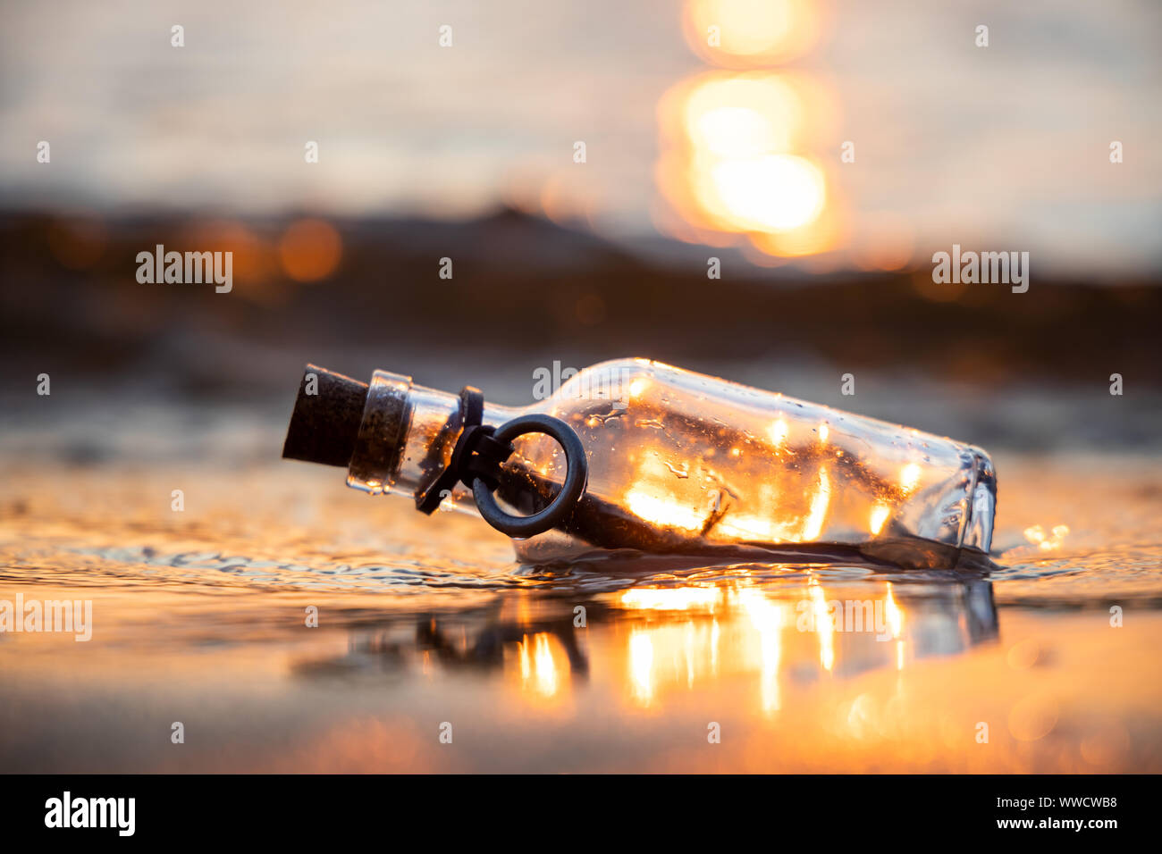 Messaggio in bottiglia contro il sole che tramonta verso il basso Foto Stock