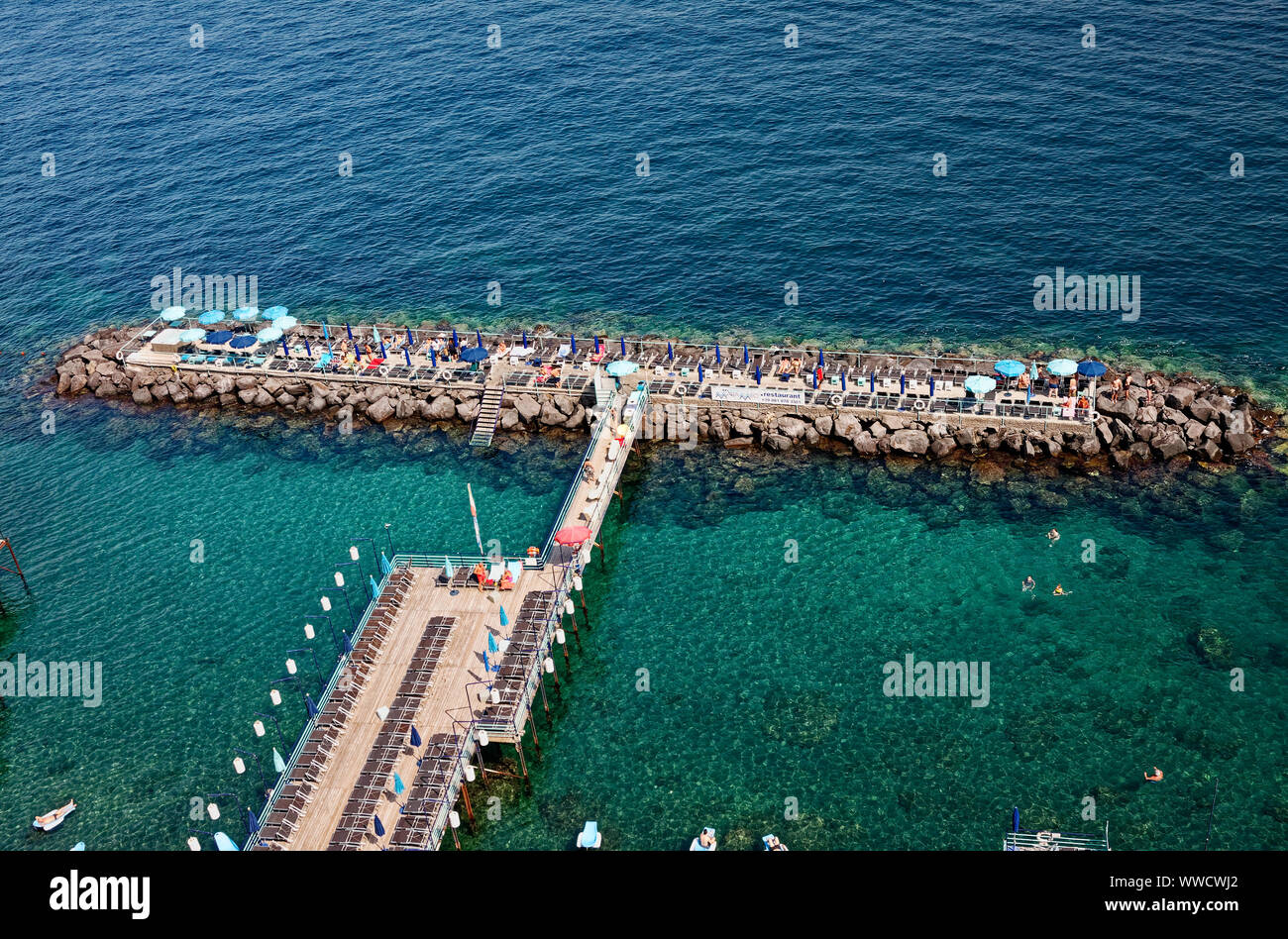 Area nuoto; coste; legno pier; pietra jetty, sedie a sdraio, ombrelloni, persone, acqua chiara, Mar Tirreno, tempo libero, vacanze, recreatikon, Sorrento; Foto Stock