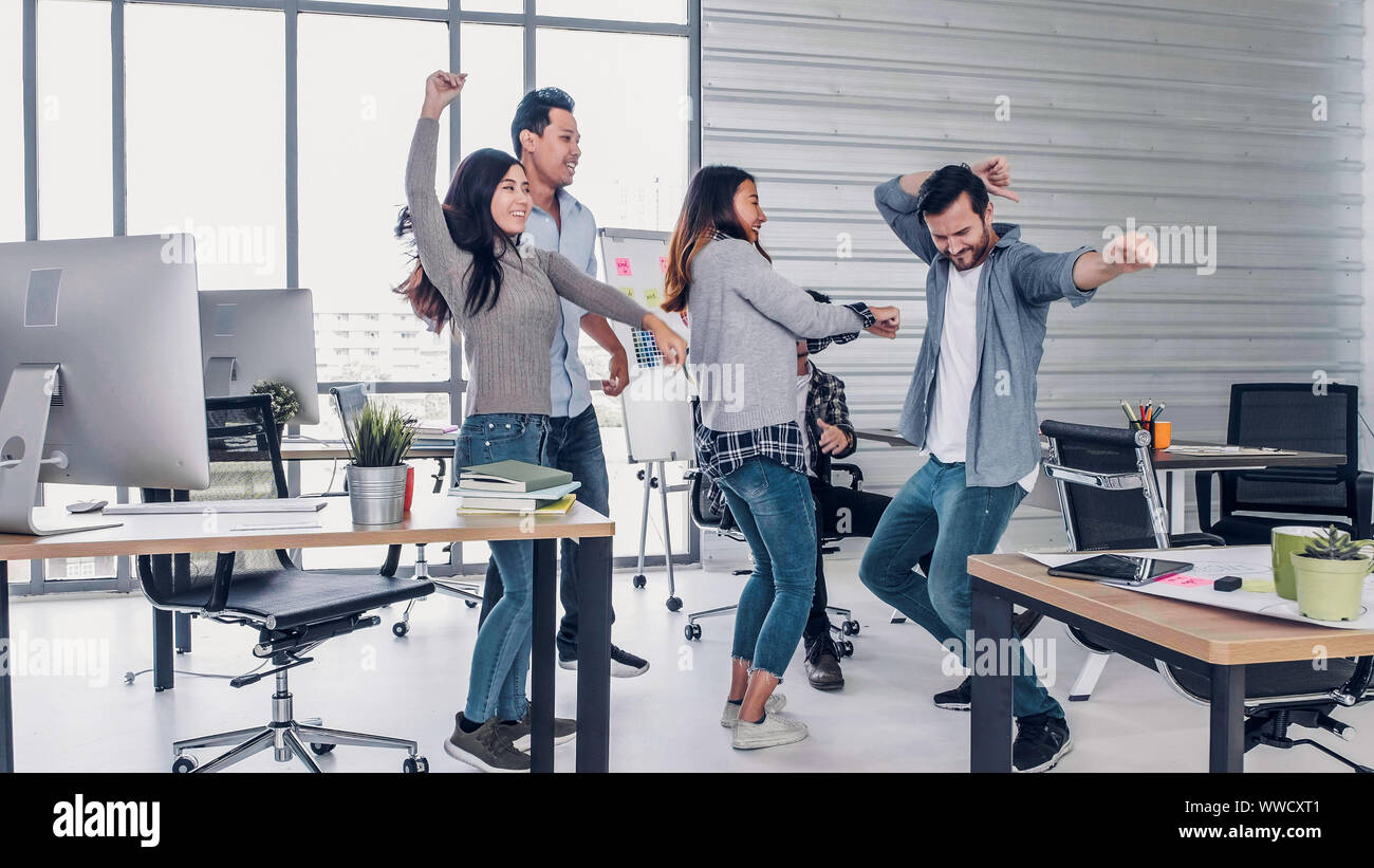 Gruppo di designer creativo dancing in ufficio con sensazione di relax e di piacere sulle buone notizie di successo del progetto presso un ufficio moderno.giorno lavorativo lifesty lavoro Foto Stock