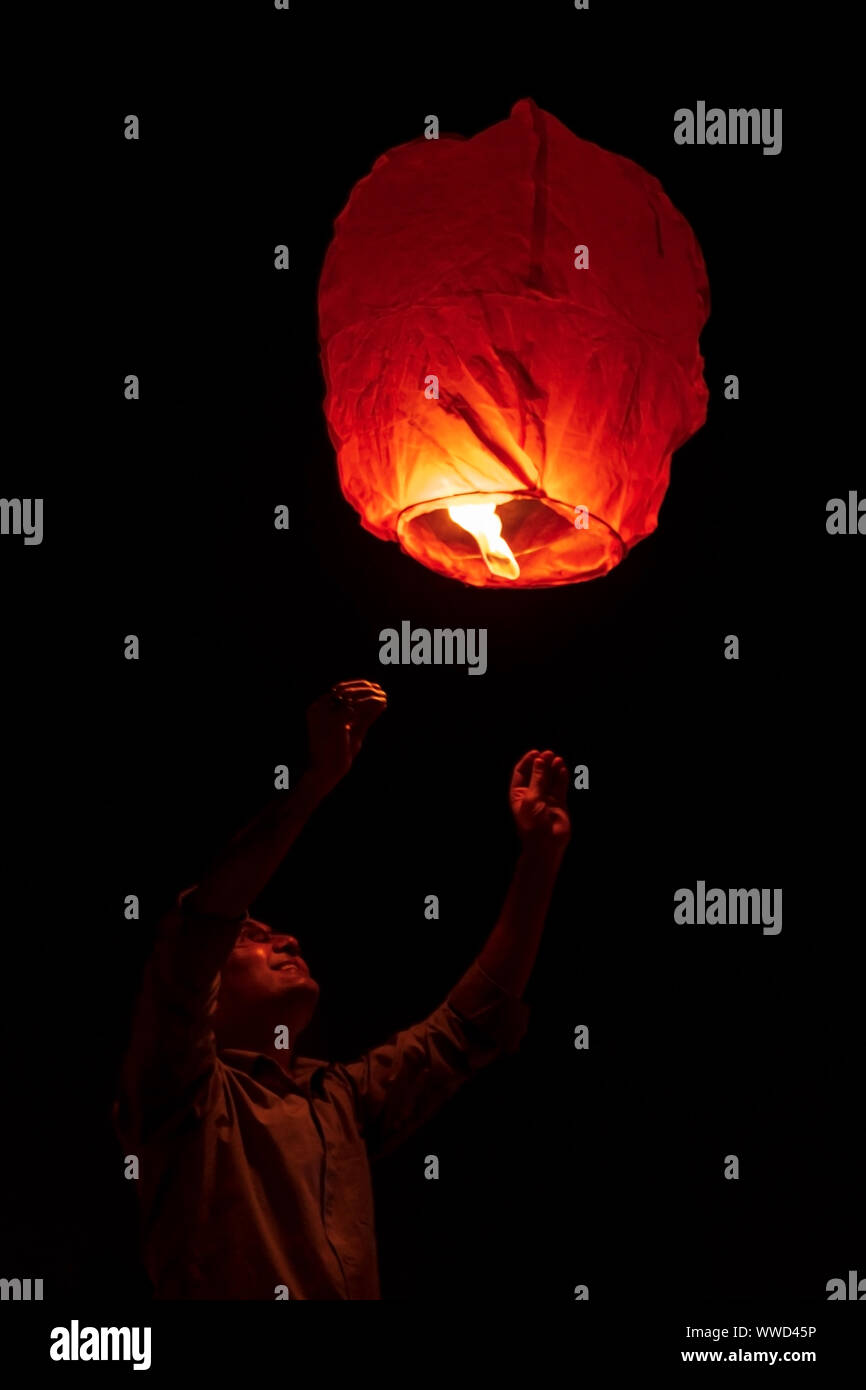 Ragazzo di lancio o battenti la carta sky lantern al cielo di notte. Concetto di sfondo per il Diwali nuovo anno celebrazione. Foto Stock