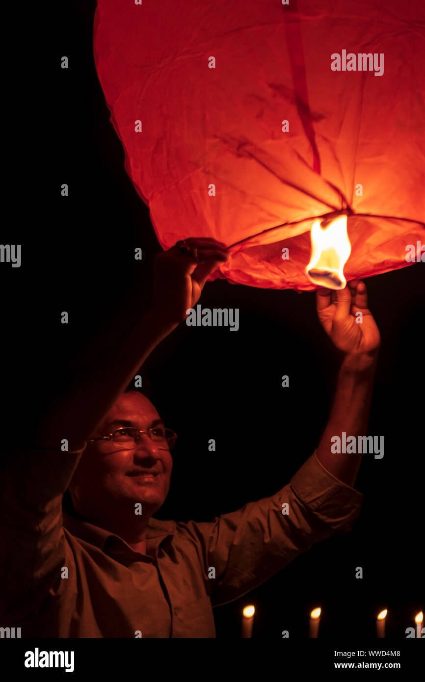 Indiano persona di sesso maschile di lancio o battenti una carta rossa lanterna del cielo di notte il Diwali o nuovo anno celebrazione. Foto Stock