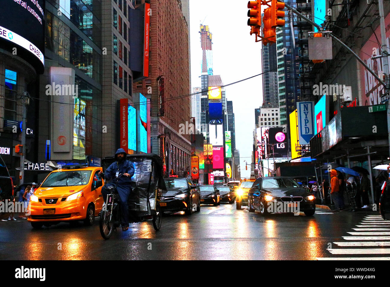 Il traffico di pedoni, ciclisti e automobili trudges attraverso Times Square in un pomeriggio piovoso. Manhattan su luglio 31st, 2019 a New York, Stati Uniti d'America. (Foto di Foto Stock