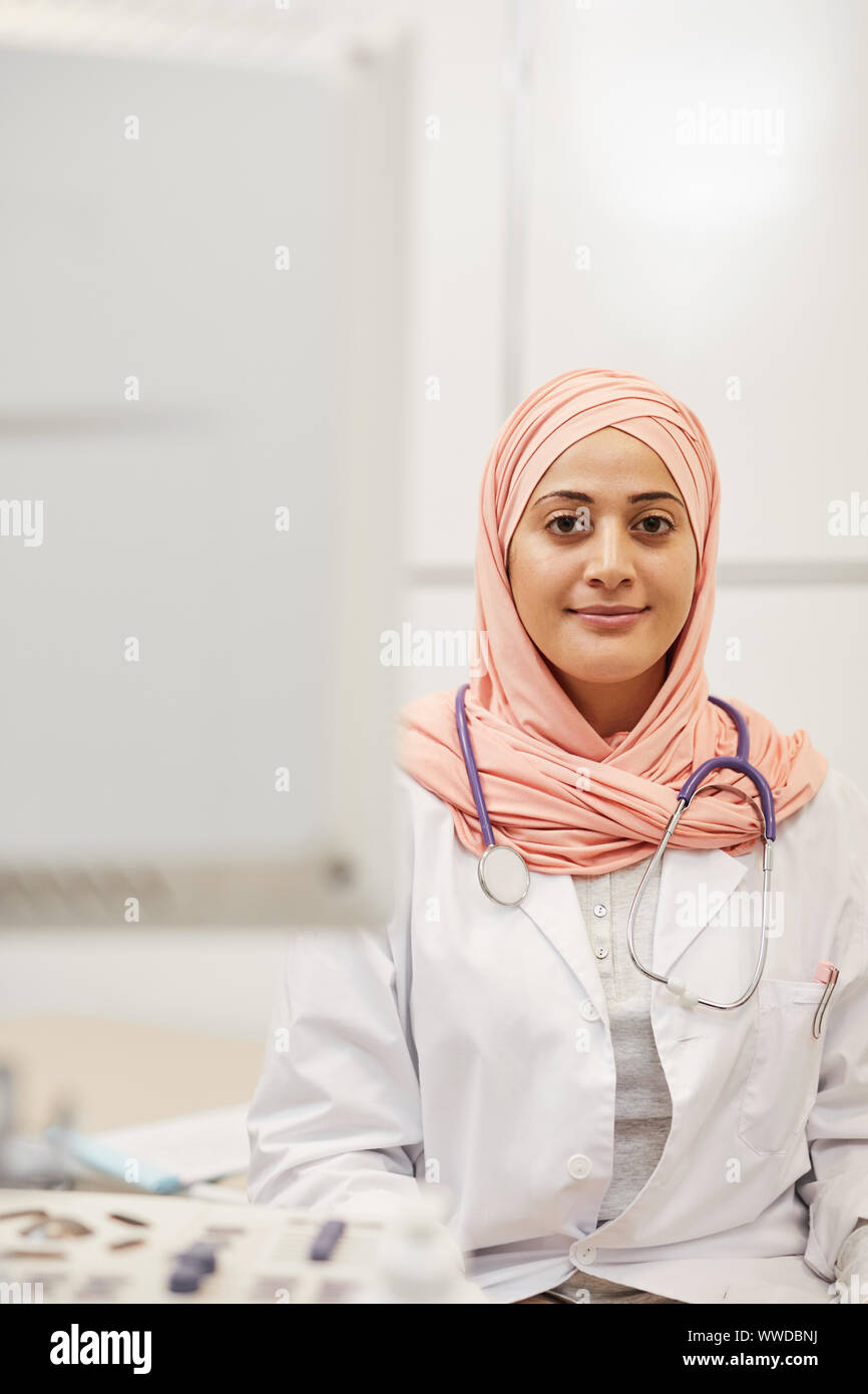 Vita ritratto di medio-orientali donna che indossa velo sorridente alla telecamera mentre in posa di medici office Foto Stock