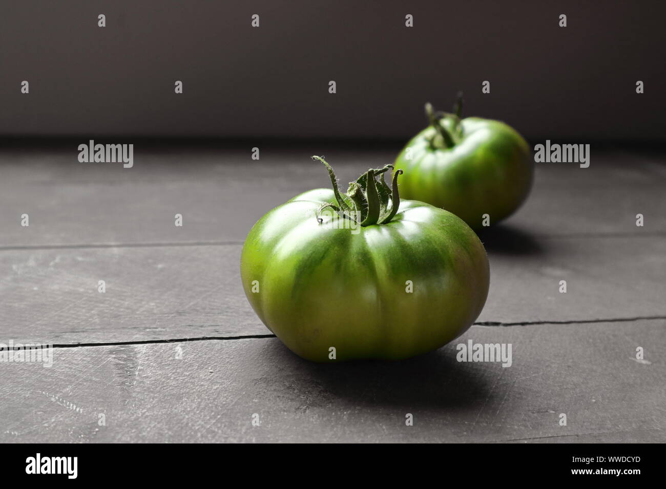 2 immaturo, patrimonio verde pomodori su una tavola in legno rustico Foto Stock