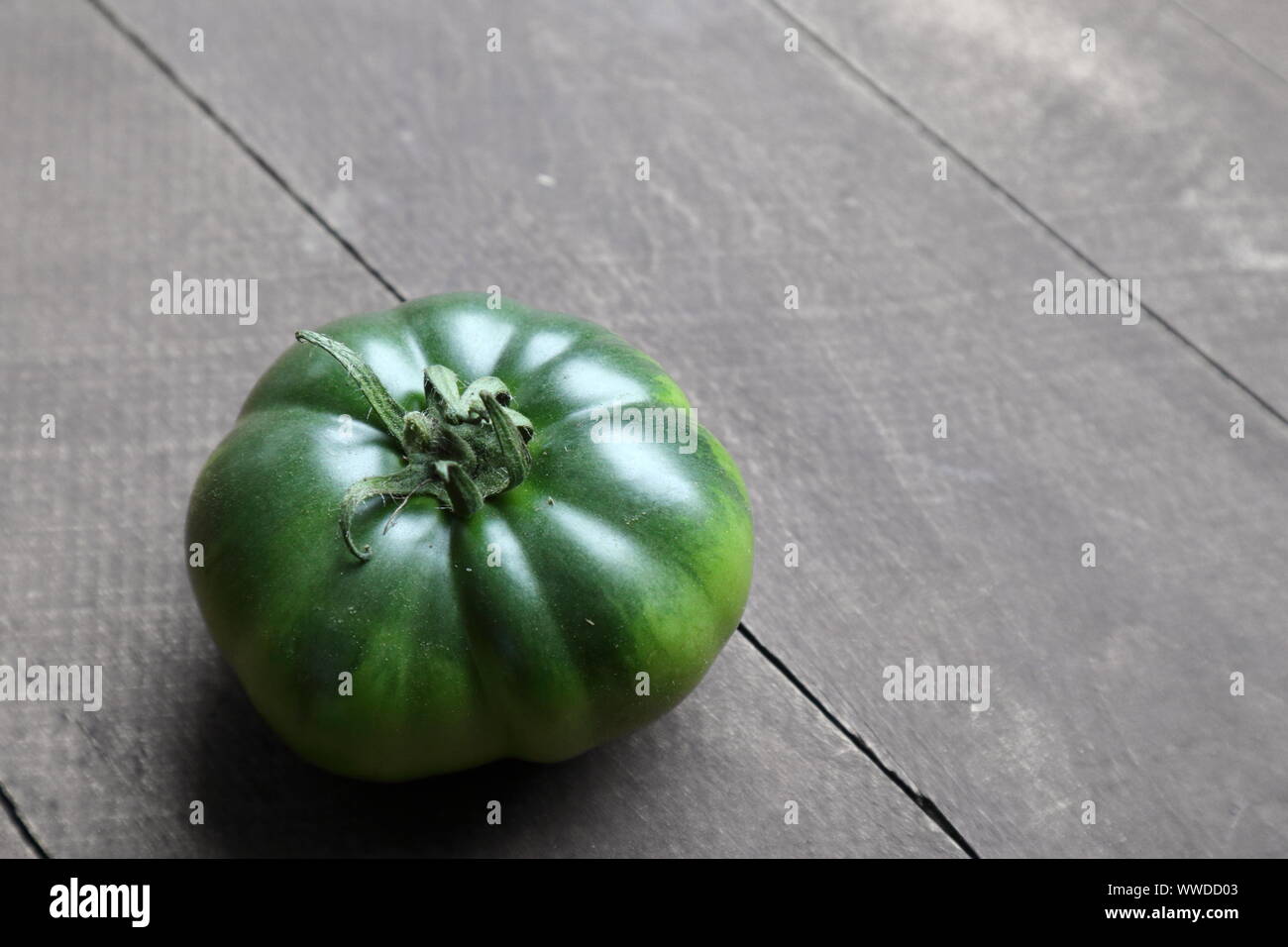 Acerbi, patrimonio verde pomodoro su una tavola in legno rustico Foto Stock