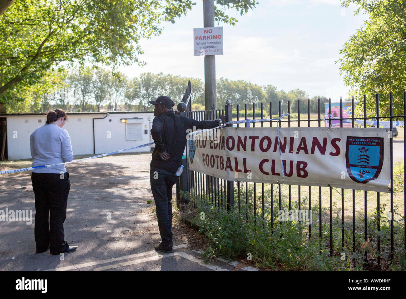 Un membro del pubblico parla con un poliziotto al di fuori dell'Old Edmontonians Football Club a Jubilee Park, Edmonton, a seguito dell'uccisore di un uomo di 29 anni. Gli ospiti della festa di compleanno che frequentano una festa alla clubhouse Old Edmontonians FC, sedettero sull'aggressore sospetto fino a quando la polizia non arrivò dopo l'attacco a nord di Londra, un testimone ha affermato. Foto Stock