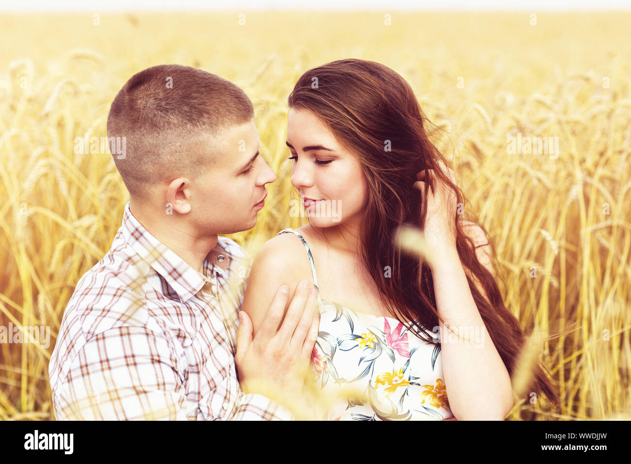 Una ragazza in amore e il suo fidanzato sono avvolgente su un campo di grano. Famiglia campeggio Foto Stock