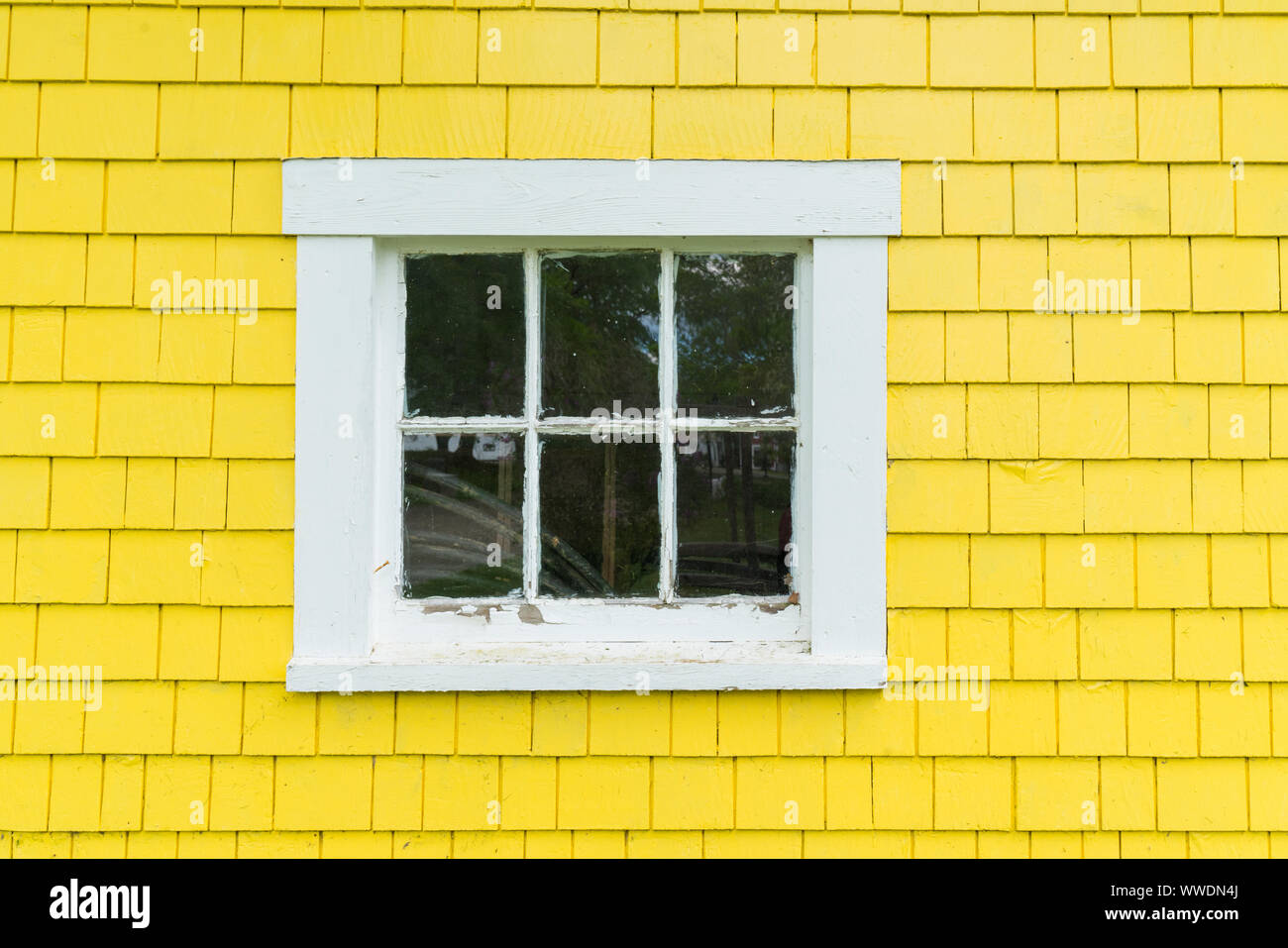 Il vecchio telaio in legno finestra con colore giallo brillante clapboard schierata Foto Stock