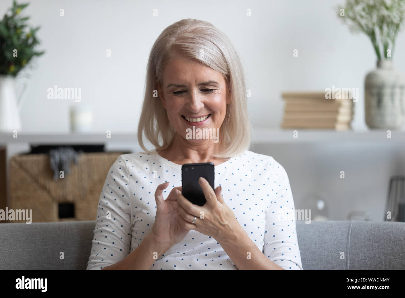 Sorridente donna matura azienda telefono, utilizzando il dispositivo mobile apps Foto Stock