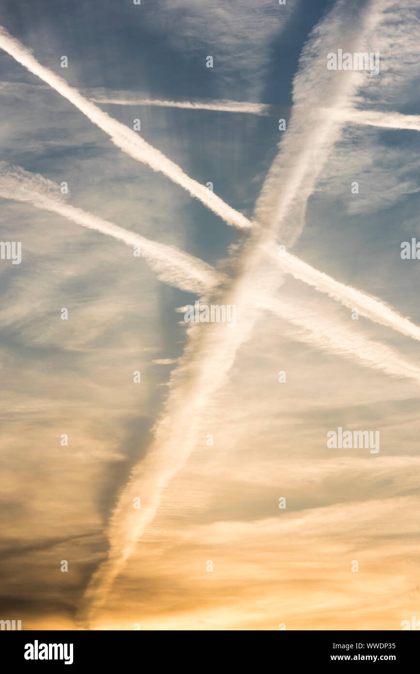 Molti sentieri di vapore da velivoli passeggeri attraversano il cielo di sera al di sopra di Zurigo, Svizzera, durante il tramonto. Foto Stock