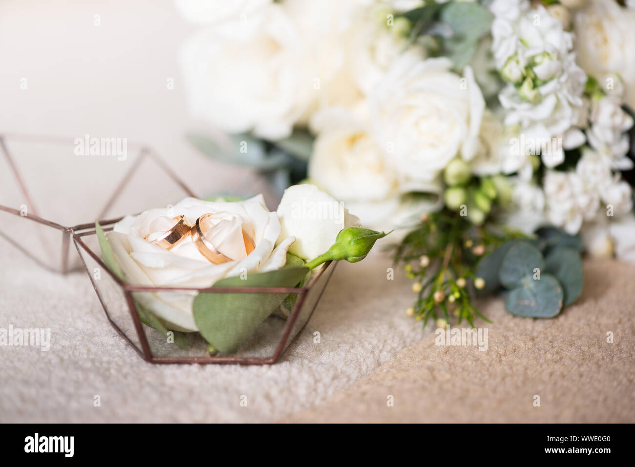 Due anelli di nozze nella bella scatola e bouquet di fiori. Temi di impegno, dichiarazione di amore, giorno di nozze, fioraio servizi. Foto Stock