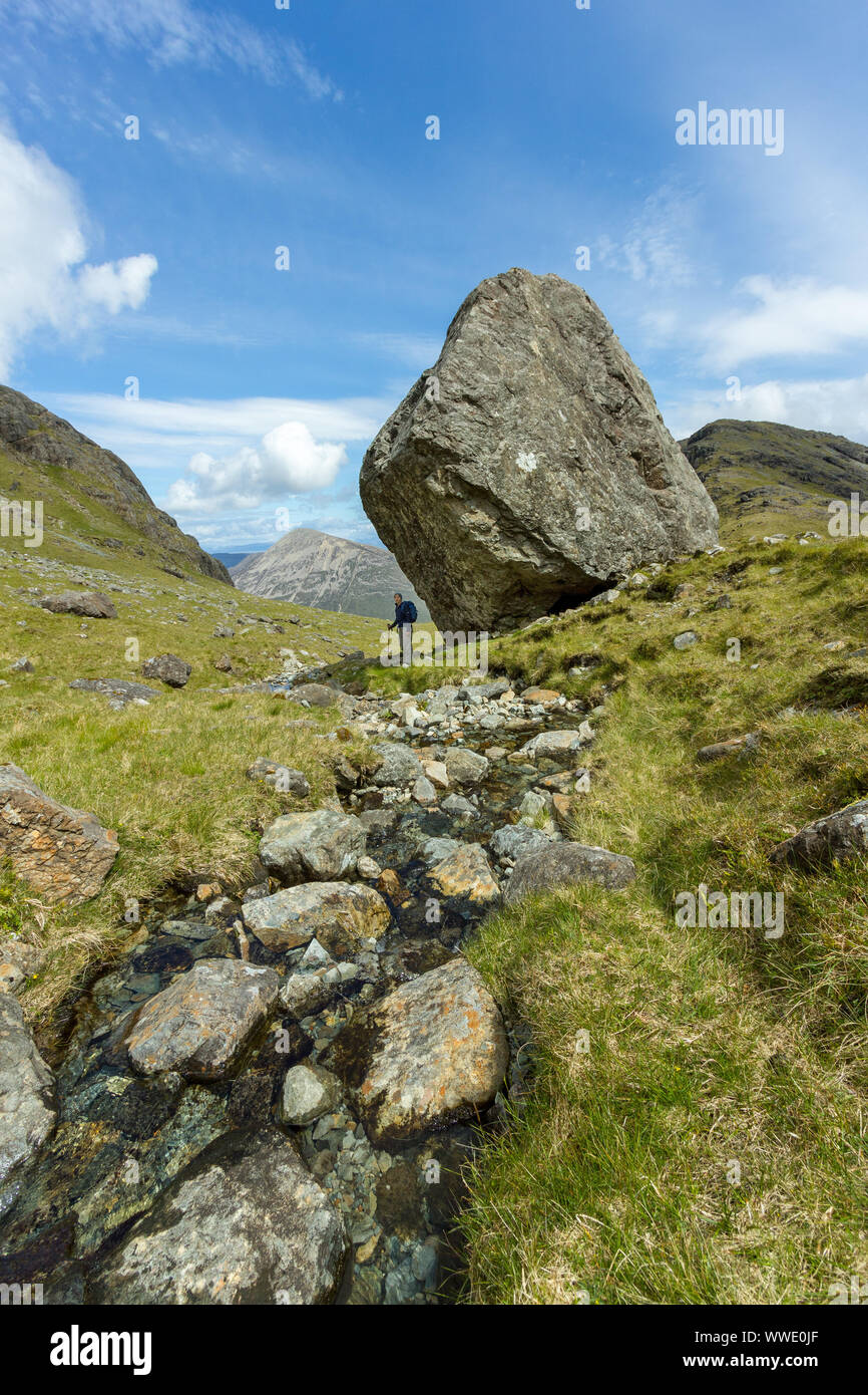 Hill-walker in piedi accanto a un enorme masso, Fionna Choire, Blaven, Isola di Skye, Scotland, Regno Unito Foto Stock