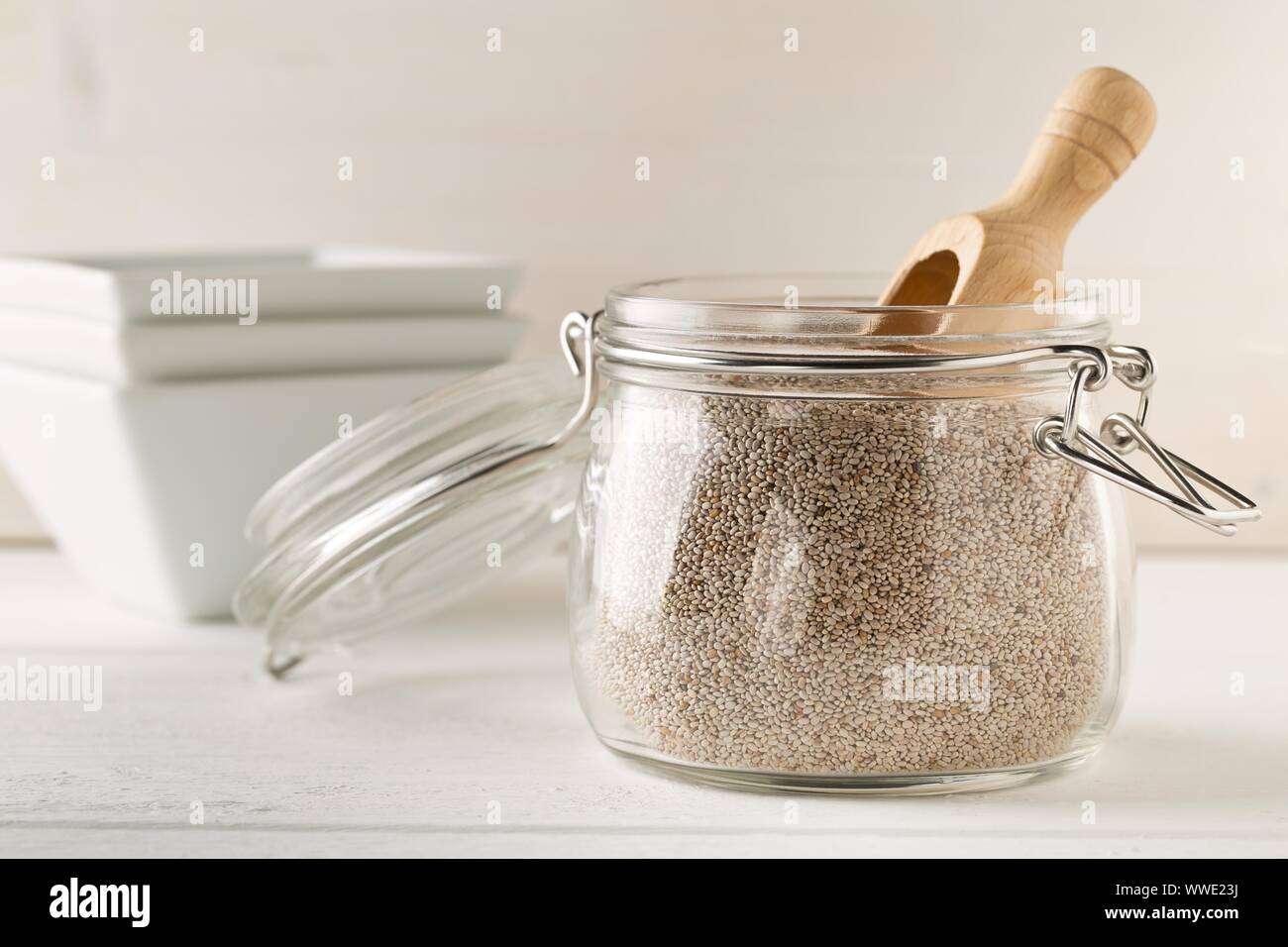 Tutto, organico bianco semi di chia mucchio nel vetro vaso di storage sul tavolo bianco lo sfondo con il fuoco selettivo Foto Stock