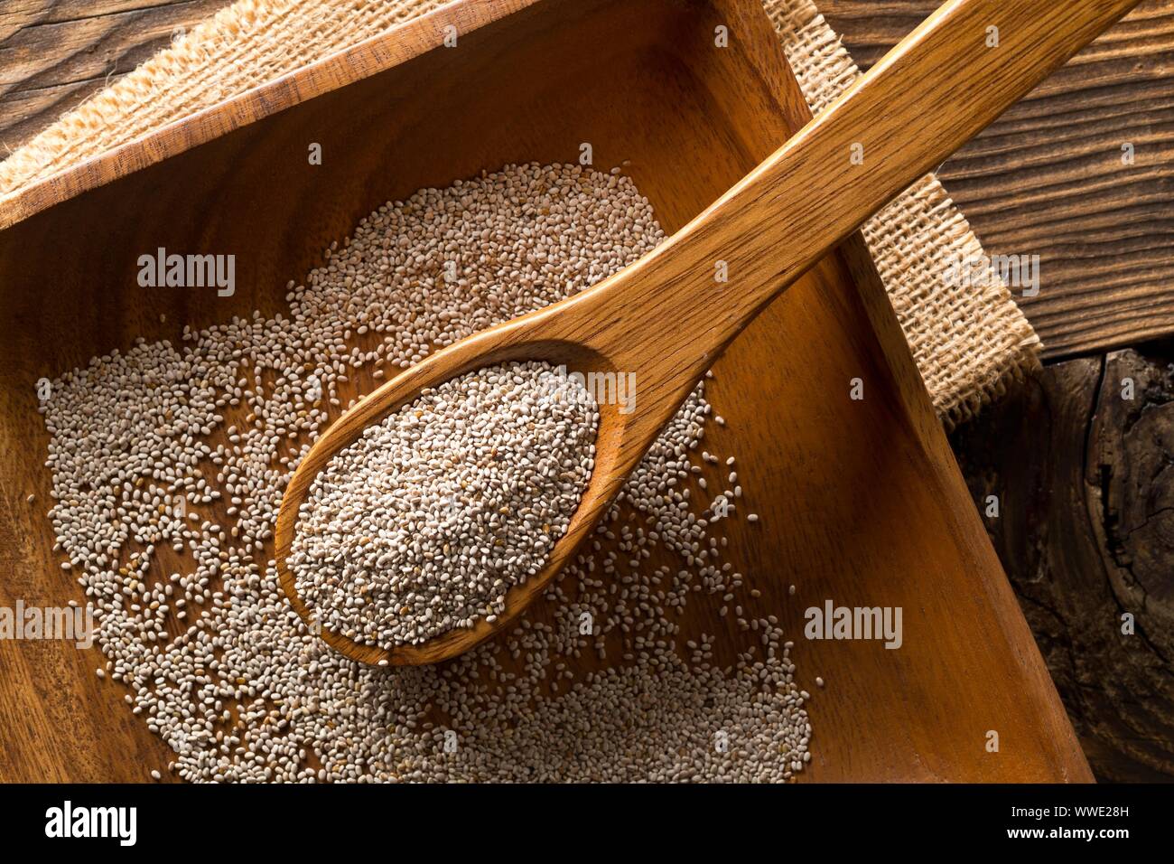 Tutto, organico bianco semi di chia mucchio nel cucchiaio woodenl sul piatto di legno e tavolo rustico sfondo laici flat top vista da sopra Foto Stock