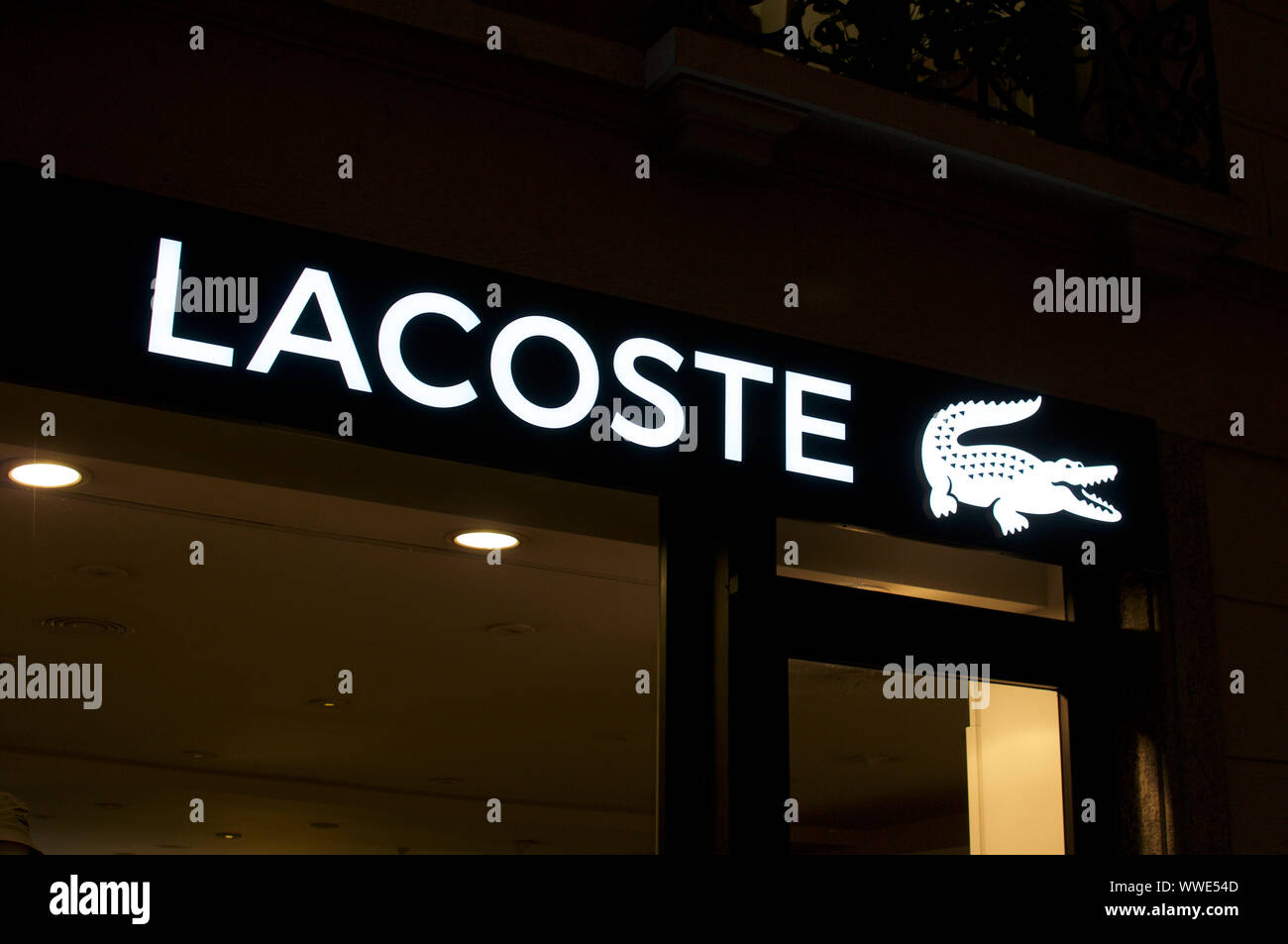 Lugano, Ticino, Svizzera - 17 Agosto 2019 : vista dell'illuminato Lacoste  logo del marchio appeso nella parte anteriore del negozio a Lugano. Lacoste  è un fren Foto stock - Alamy