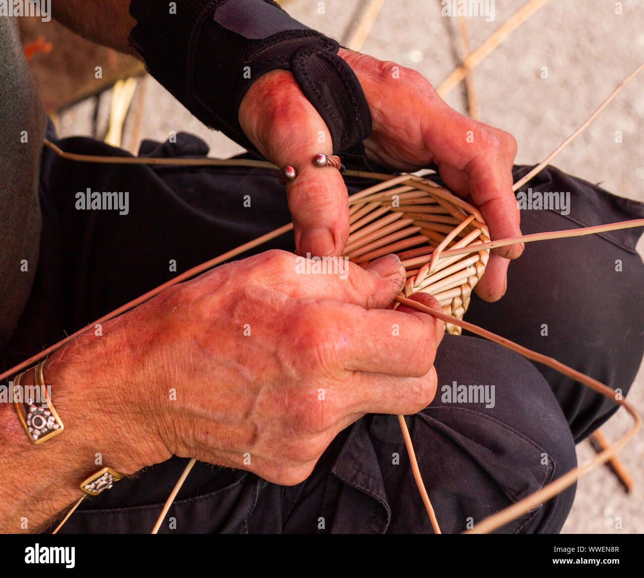 Close up di un cestello maker tessitura bastoncini di salice. Foto Stock