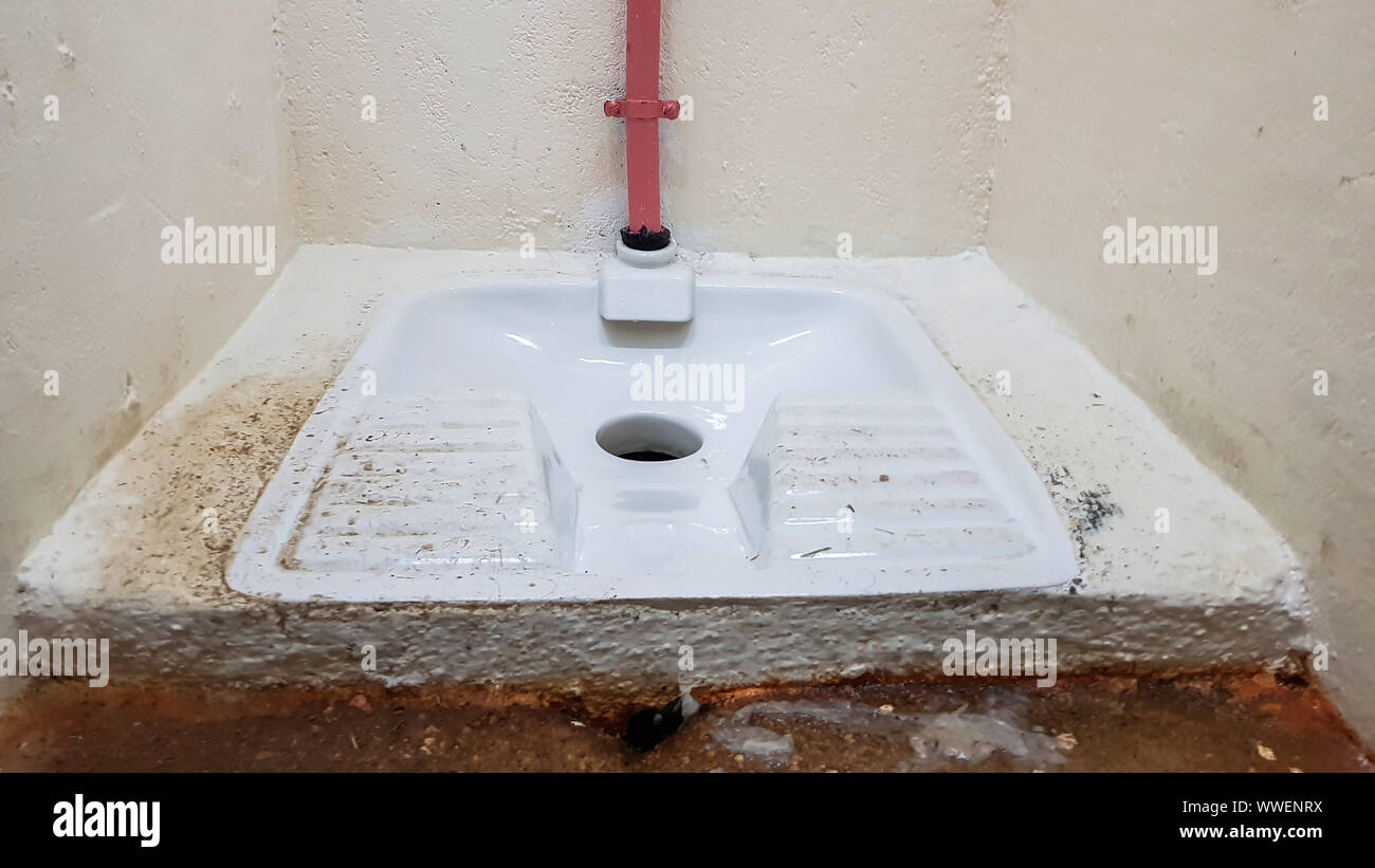 Esegui uno squat toilette in una toilette pubblica Foto Stock