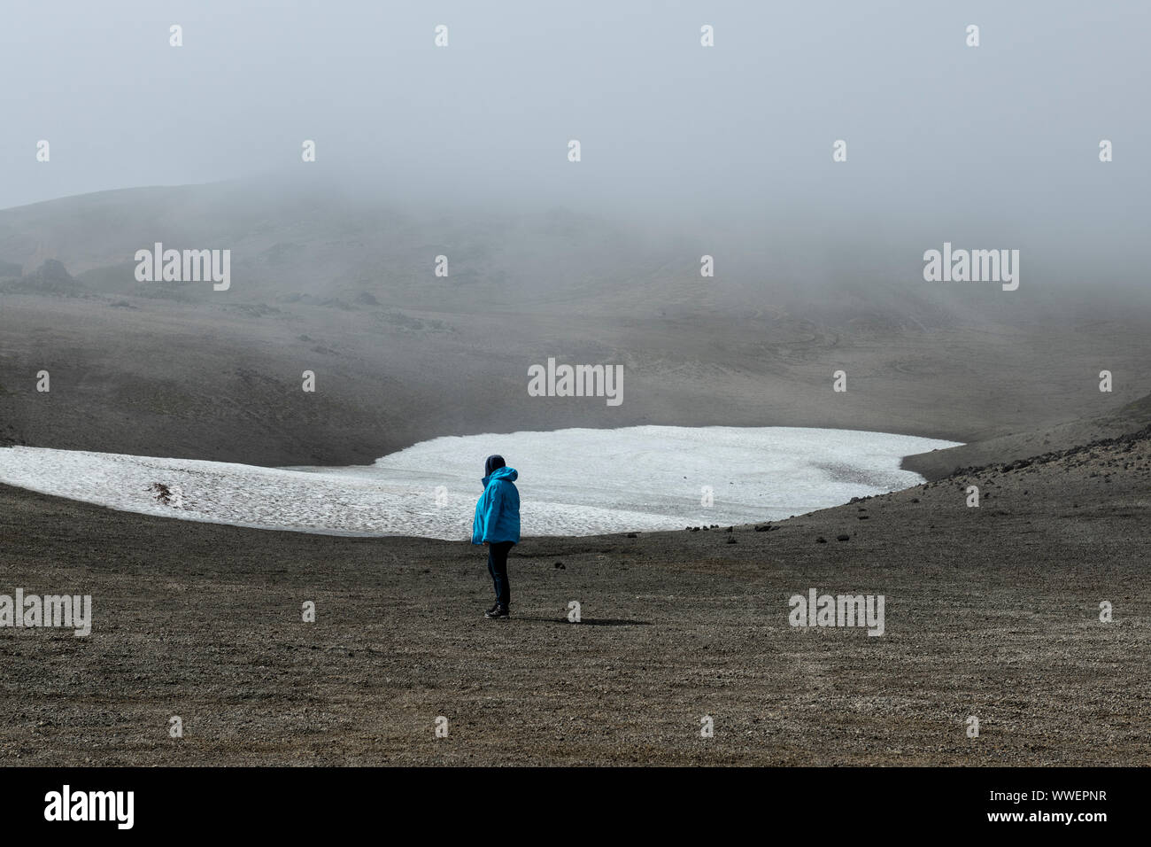 Escursionista singolo che cammina sulla lingua del ghiacciaio Snaefellsjoekull durante l'estate e indossa una giacca blu Foto Stock