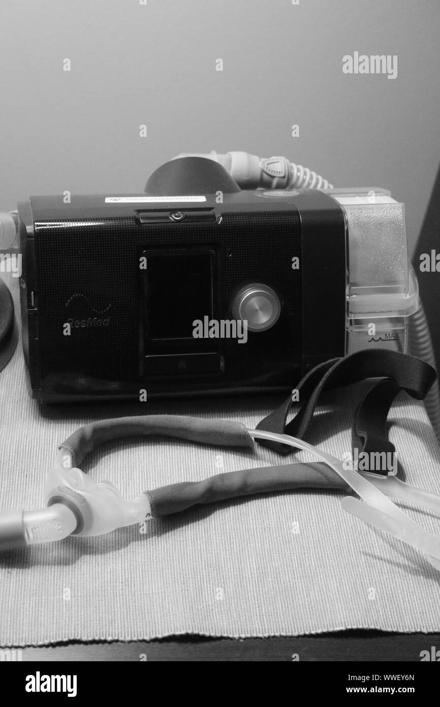 Macchina CPAP, tubo flessibile e maschera nasale seduto su un piedistallo di notte Foto Stock