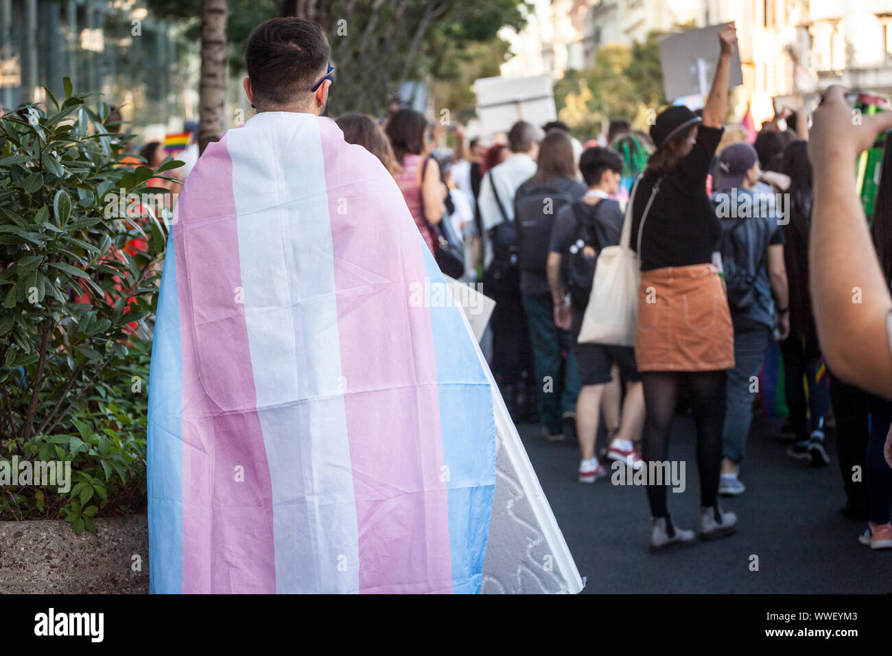 L'uomo avvolto in un transessuale bandiera visto da dietro durante il GAY PRIDE. Questo indicatore è uno dei simboli di LGBTQ e transgender gente e comunità Foto Stock