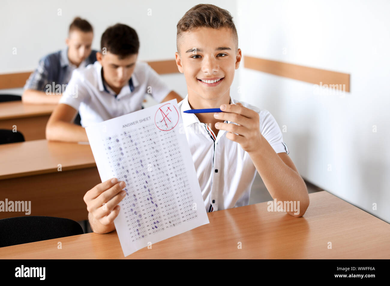 Felice ragazzo con i risultati del test di scuola in aula Foto Stock