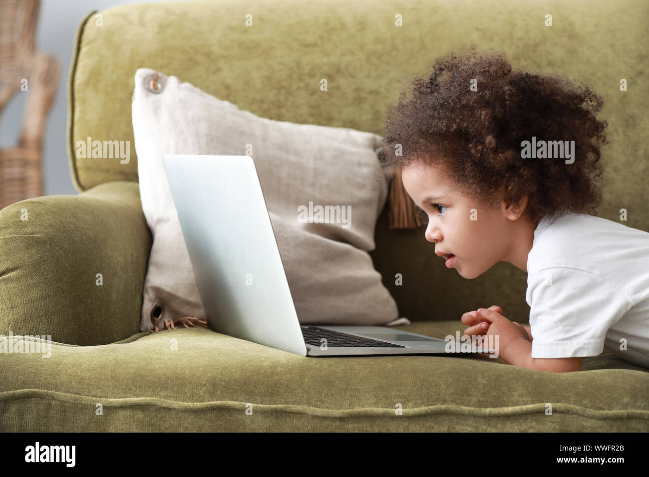 Carina ragazza afro-americano con il computer portatile guardando cartoni animati a casa Foto Stock