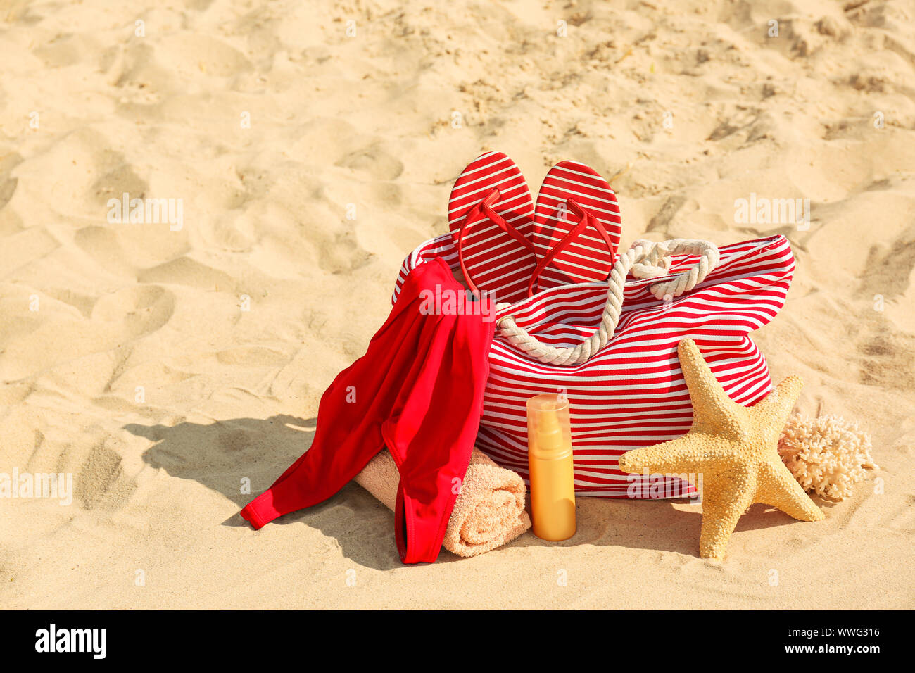 Borsa con flip-flop, costume da bagno e asciugamano e cosmetici e sulla spiaggia di sabbia Foto Stock