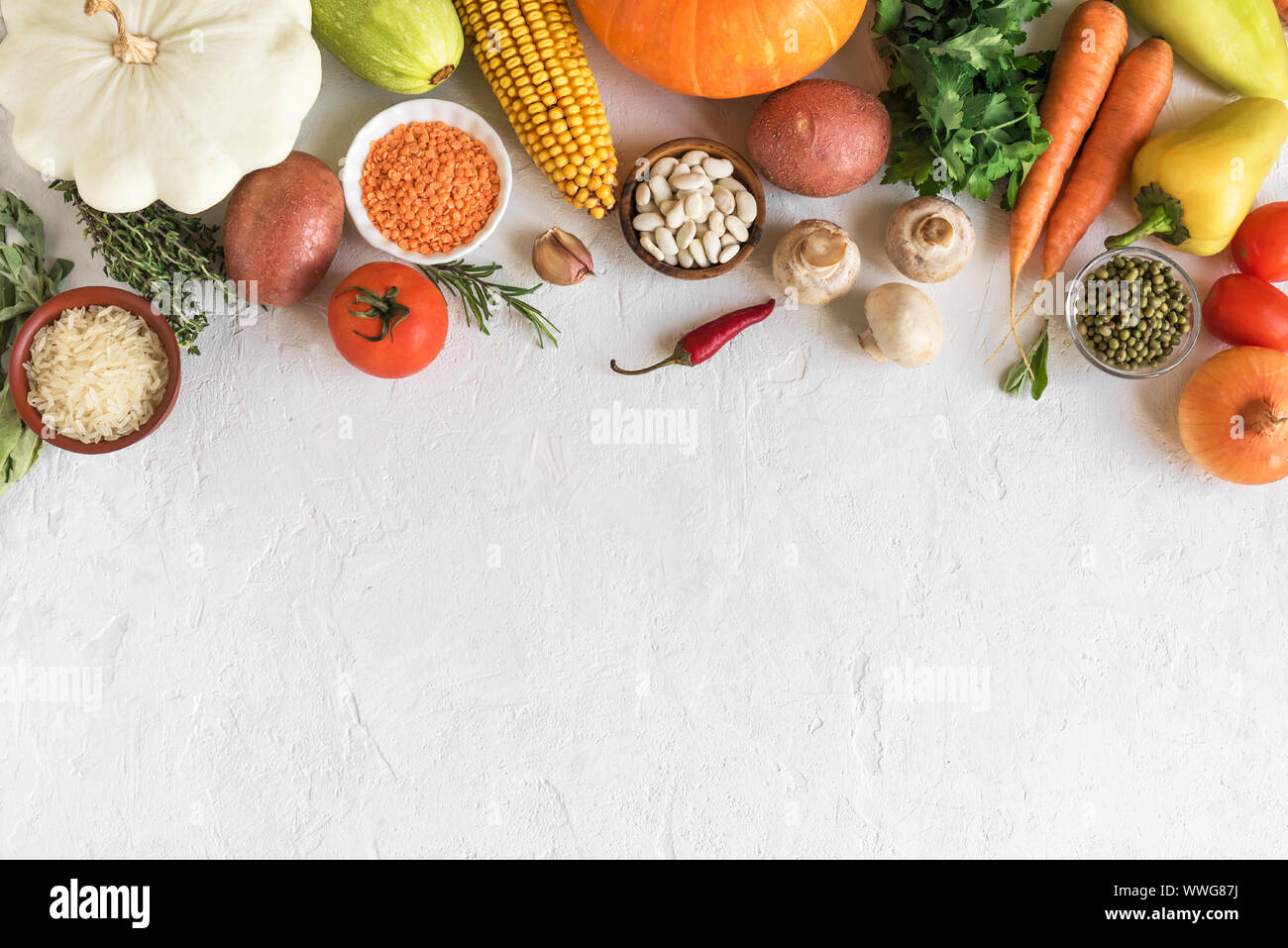 La cucina vegetariana sfondo stagionale con verdure biologiche e grani sul bianco, vista dall'alto, banner. Ingredienti per vegetariano vegano zuppe stagionali Foto Stock