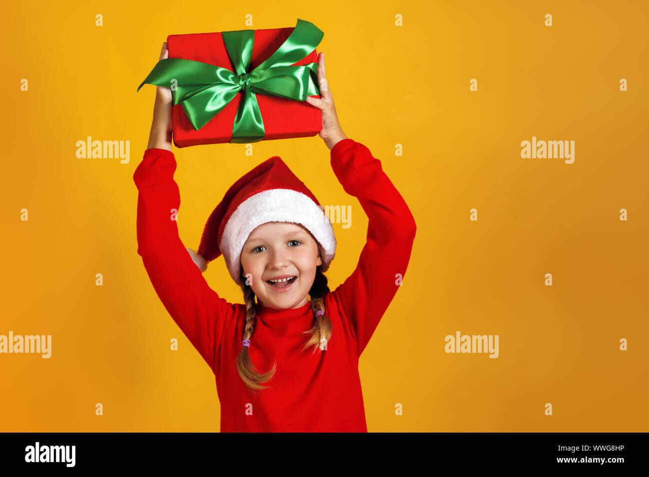 Felice bambina con il regalo di Natale. Il bambino tiene una scatola sopra la sua testa Foto Stock