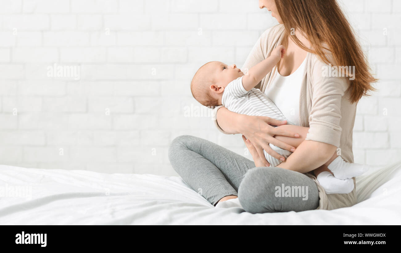 Giovane madre lulling neonato nelle sue braccia Foto Stock