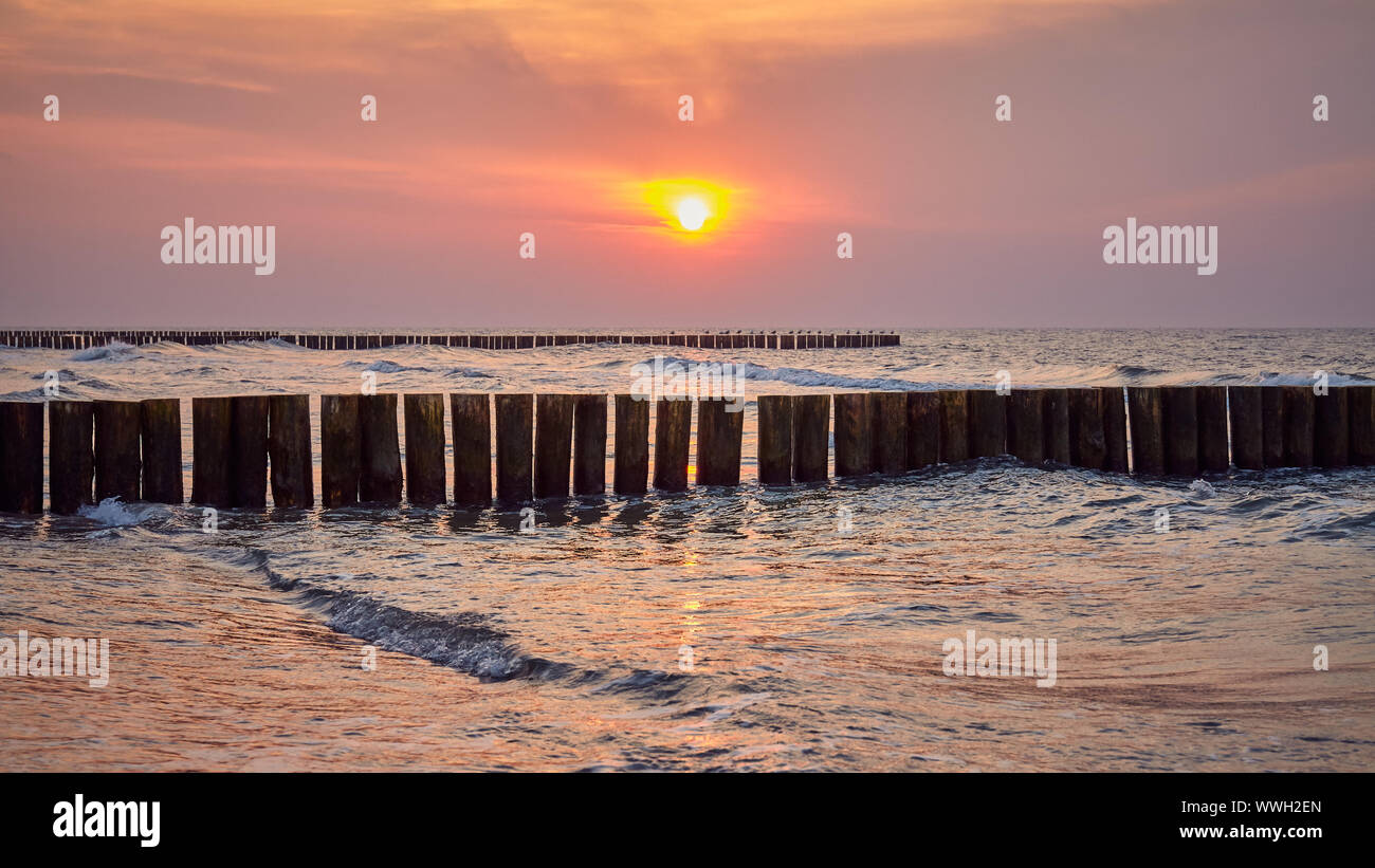 Struttura di frangionde in legno visto da una spiaggia al tramonto, Polonia. Foto Stock