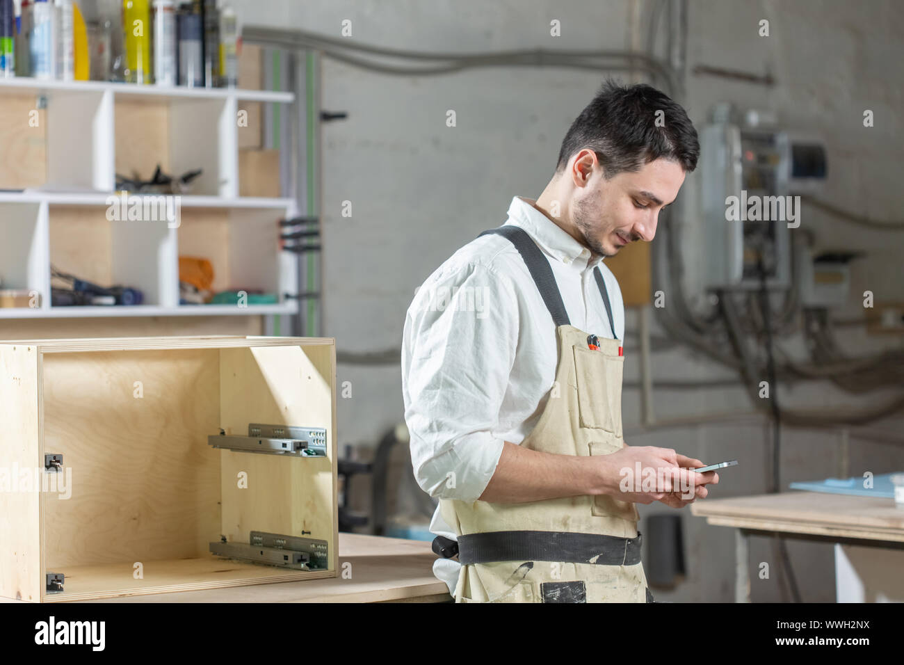 Mobili fabbrica, piccole aziende e persone concetto - giovane lavoratore lavora in una fabbrica per la produzione di mobili Foto Stock