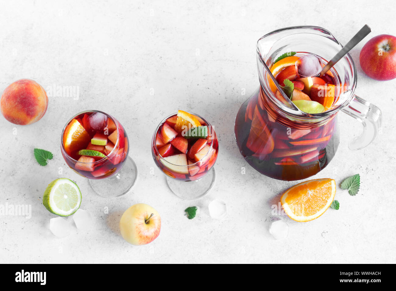 Vino rosso sangria o punzone con succhi di frutta e ghiaccio in bicchieri e brocca. In casa di frutta rinfrescante sangria su sfondo bianco, copia dello spazio. Foto Stock