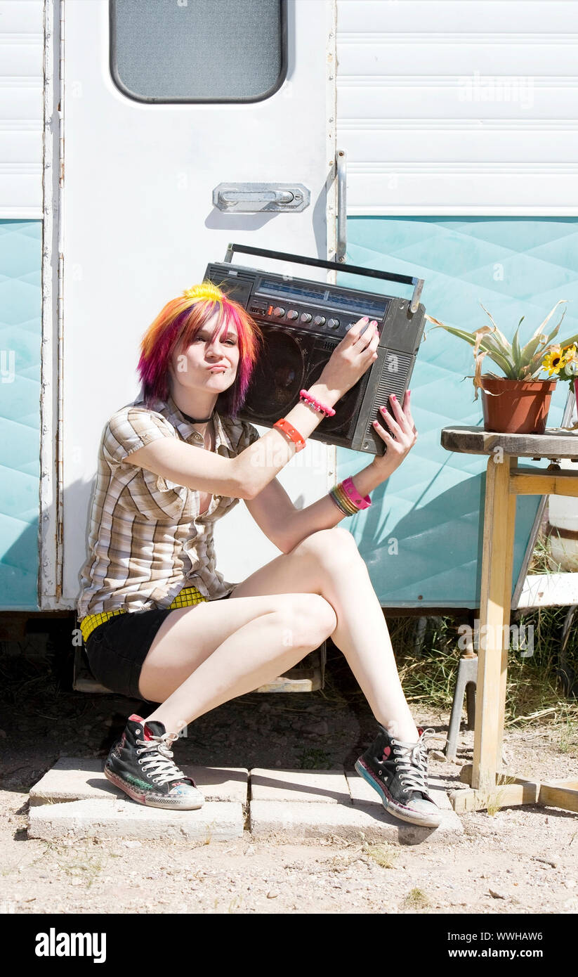 Ragazza punk con brillantemente i capelli colorati seduta sul rimorchio passo tenendo boom box Foto Stock