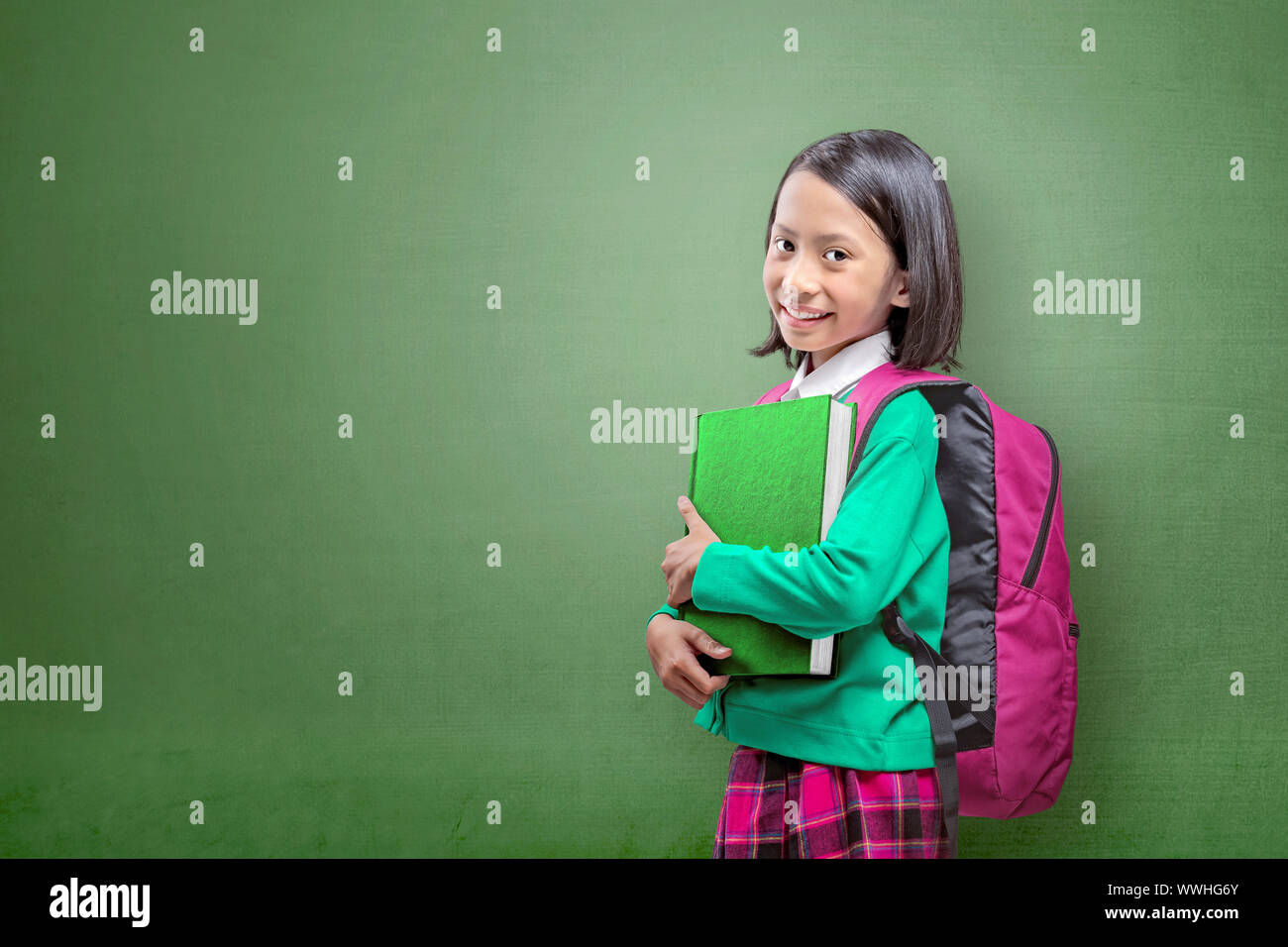 Asian Italian con uno zaino che tiene il libro in piedi con uno sfondo verde Foto Stock