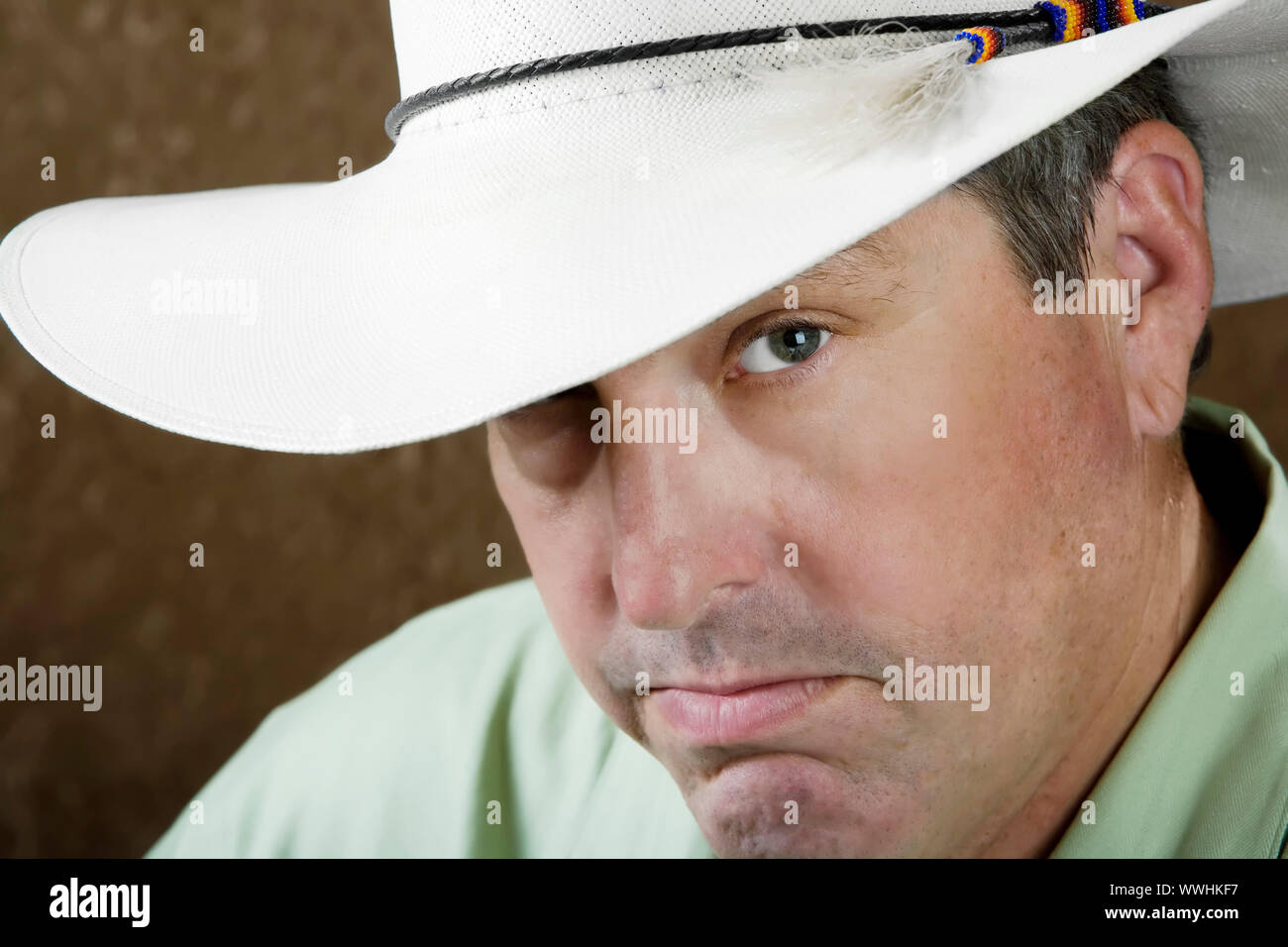 Uomo al di sotto di una bianca cappello da cowboy di fronte a fondo oro Foto Stock