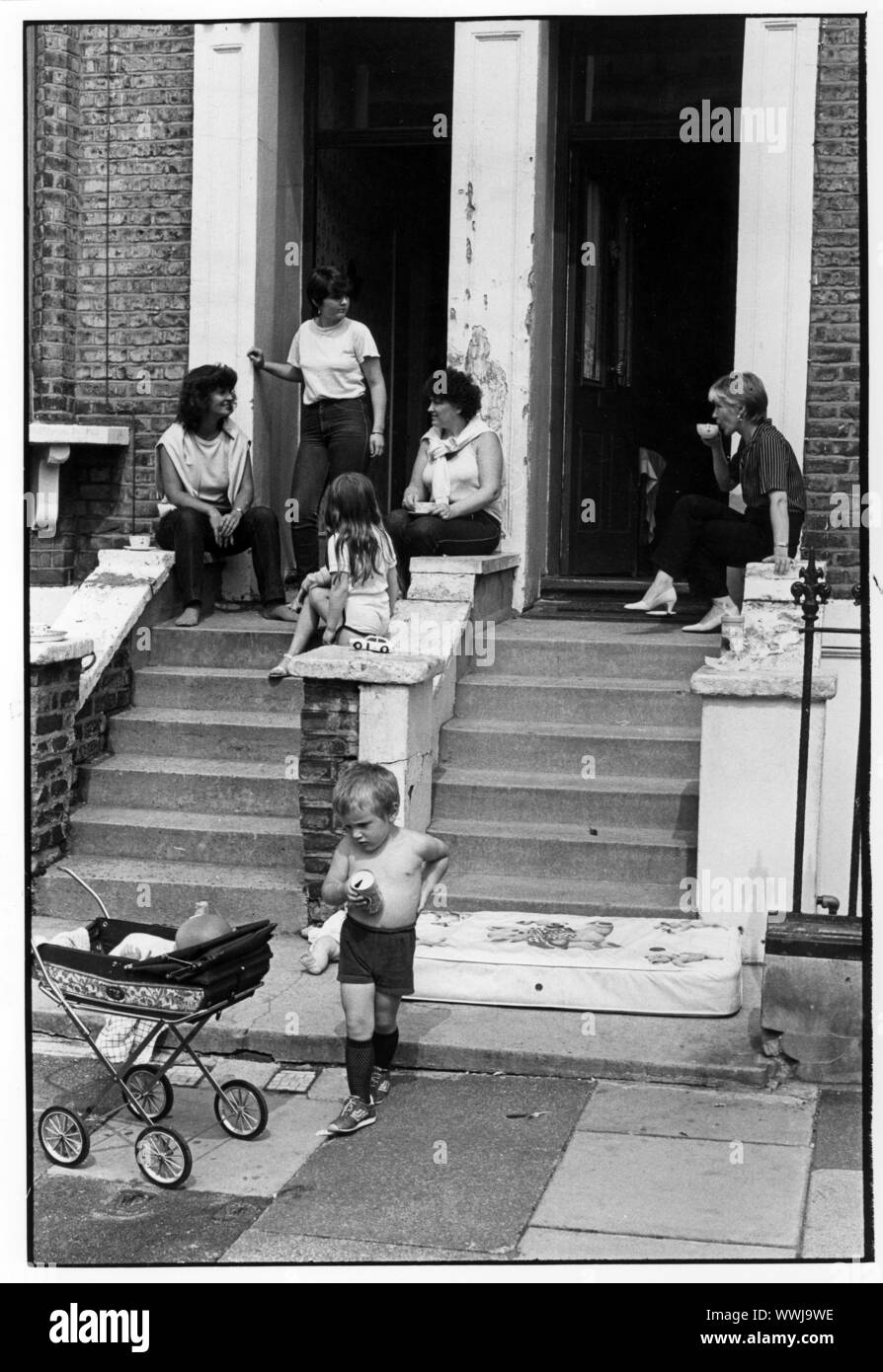 Negli anni settanta le donne con bambini seduti sui gradini di case nella zona ovest di Londra Foto Stock