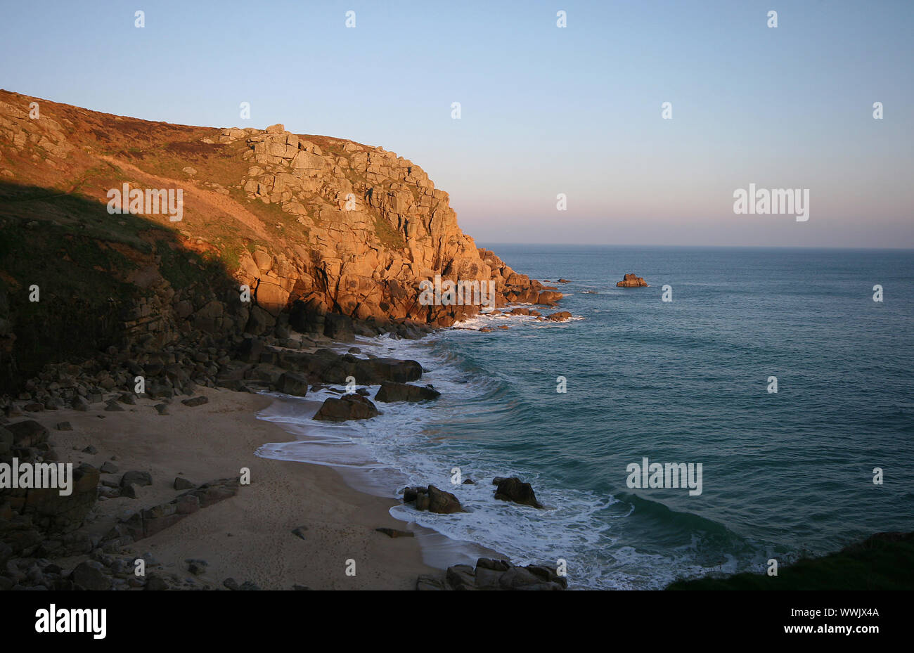 Il sole di sera dà un colore dorato per la capezzagna a Porthchapel allo stesso tempo getta un' ombra sulla spiaggia dopo una giornata piena di persone. Foto Stock