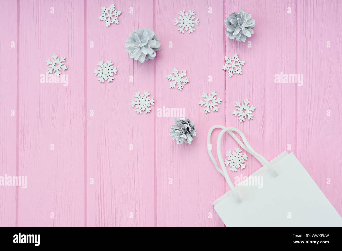 Regalo di Natale sfondo di incarto. Piatto con laici Bianco confezione artigianale e i coni e i fiocchi di neve sul rosa sullo sfondo di legno. Moderna composizione in Foto Stock